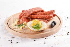Wooden chopping board with sausages, cheese, bread