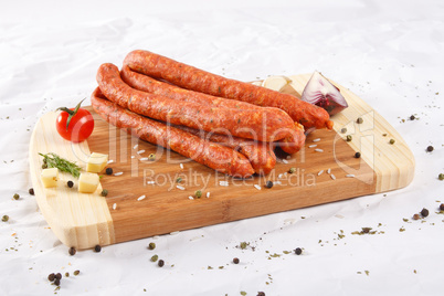 Wooden chopping board with sausages and spices