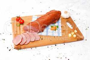 Wooden chopping board with sliced ham and spices