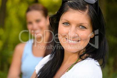Mother smiling with teen daughter in background