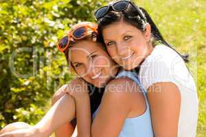 Mother and teen daughter hugging outdoors relaxing