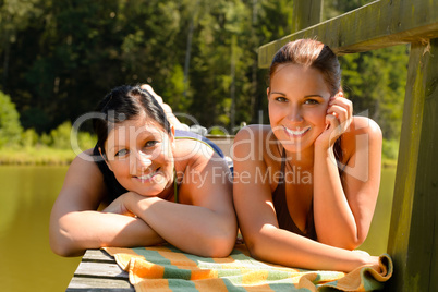 Mother and daughter sunbathing on pier smiling