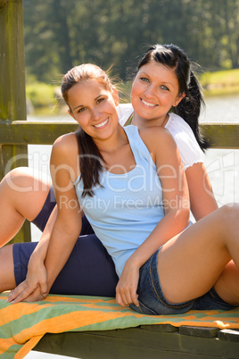 Daughter and mother sitting on pier relaxing