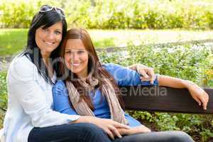 Mother and daughter relaxing on park bench