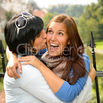 Mother kissing her daughter happy embrace outdoors