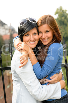 Daughter and mother embracing outdoors happy teen