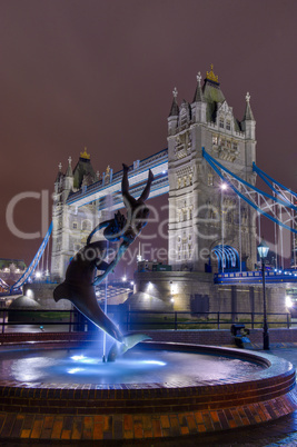 statue facing the tower bridge by night