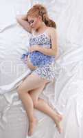 Beautiful pregnant woman sleeping in silk bed
