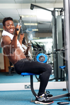 Fit african trainer working out in multi gym