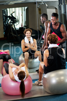 Trainer instructing gym clients on how to use exercise ball