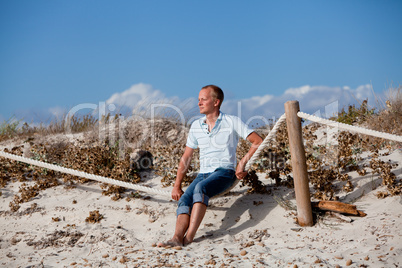 junger mann entspannt am strand in dünen