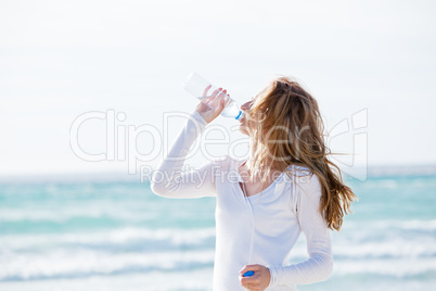 junge hübsche frau trinkt wasser am strand im urlaub