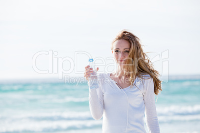 junge hübsche frau trinkt wasser am strand im urlaub