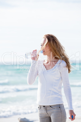 junge hübsche frau trinkt wasser am strand im urlaub