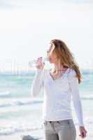 junge hübsche frau trinkt wasser am strand im urlaub