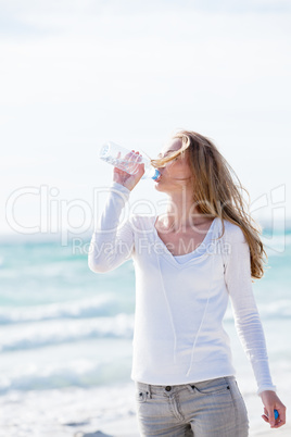 junge hübsche frau trinkt wasser am strand im urlaub