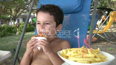Little boy eating burger and fries