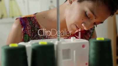 Hispanic woman working as fashion designer with sewing machine