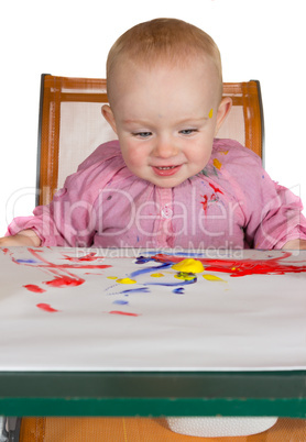 Happy baby girl playing with paint
