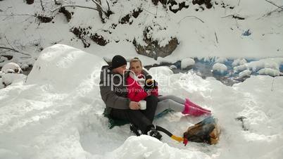 Couple Sitting by Bonfire in Winter Forest