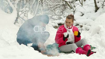 Winter Holidays by Bonfire in Snowy Forest