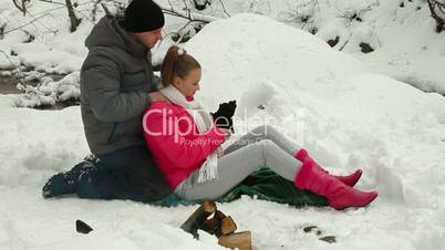 Teenagers Sitting by Bonfire in Winter Forest