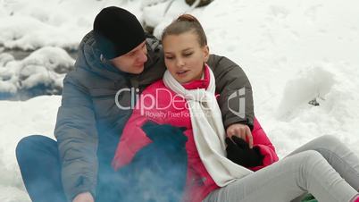 Teenagers Warming Up by Bonfire in Winter Forest