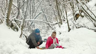 Teenage Couple in Winter Forest By Bonfire