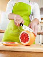 Woman's hands cutting grapefruit