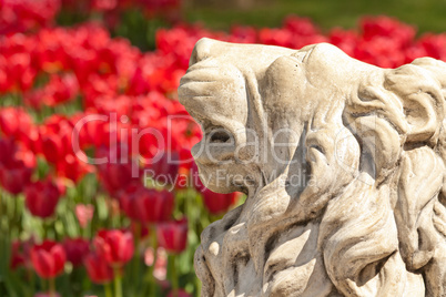 A Stone Lion Statue in a Yard Setting With Flowers