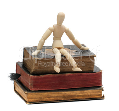wooden doll sit on old books