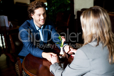 Romantic couple sitting across the table and holding hands