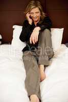 Pretty woman relaxing in bed and talking on phone