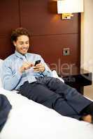 Man resting in luxurious bed and messaging