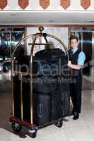 Bell boy pushing cart loaded with luggage