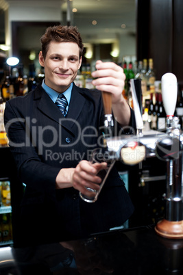 Handsome mixologist putting ice into tall glass