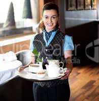 Pretty waitress posing with tea for guests