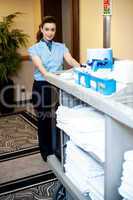 Beautiful employee psuhing housekeeping cart