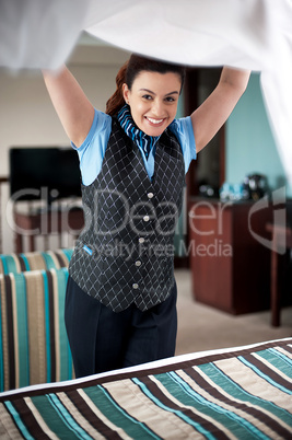 Charming female housekeeper replacing the sheets