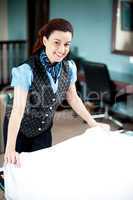 Beautiful smiling attendant holding sheet, redoing room