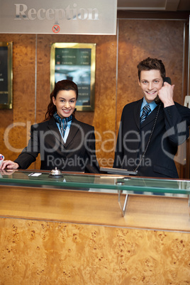 Male and female at hotel reception busy working