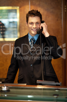 Cheerful front desk executive attending phone call