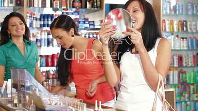 Female Friends Testing Lipstick in Beauty Department
