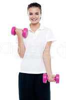 Smiling fitness teenage girl lifting weights