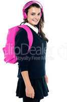 Schoolgirl with pink backpack and matching headphones
