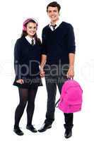Boy holding pink backpack posing with female student