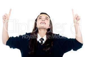 Excited young teenage girl looking and pointing upwards