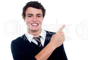 Cheerful schoolboy pointing at copy space area
