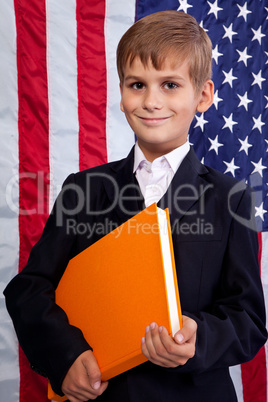 Ñute schoolboy is holding a book against USA flag