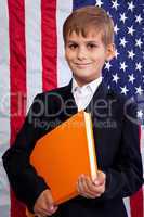 Ñute schoolboy is holding a book against USA flag